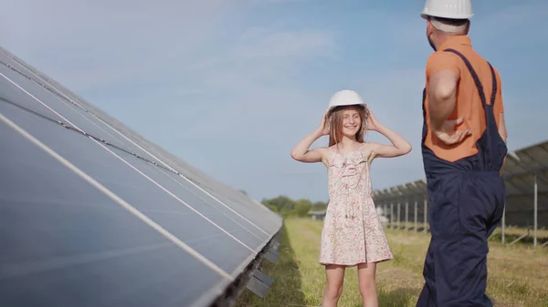 An young father is engineer explains to his little daughter an operation and performance of photovoltaic solar panels at sunset. Concept:renewable energy, technology, electricity,green,future, family