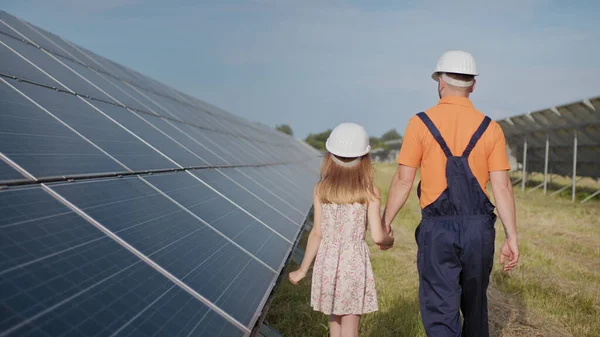 태양 발전소에서 일하는 한 아버지는 딸에게 자신의 일에 대해 이야기하고, 녹색 에너지, 태양 전 지판을 보여 줍니다. 태양열 발전소에서 촬영. 지구의 보존, 지구 온난 화 — 스톡 사진