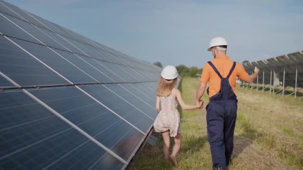 Ein Vater, der in einem Solarkraftwerk arbeitet, erzählt seiner Tochter von seiner Arbeit, zeigt grüne Energie, Sonnenkollektoren. Schießen auf ein Solarkraftwerk. Erhaltung unseres Planeten, globale Erwärmung — Stockvideo