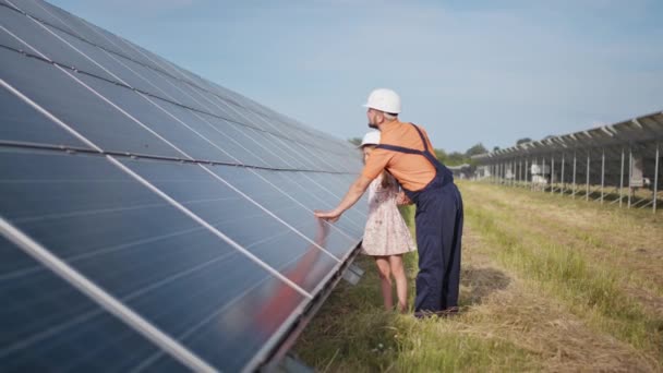 Een vader die in een zonnecentrale werkt vertelt zijn dochter over zijn werk, toont groene energie, zonnepanelen. Schiet op een zonne-energiecentrale. Het kind bestudeert zonne-energie — Stockvideo