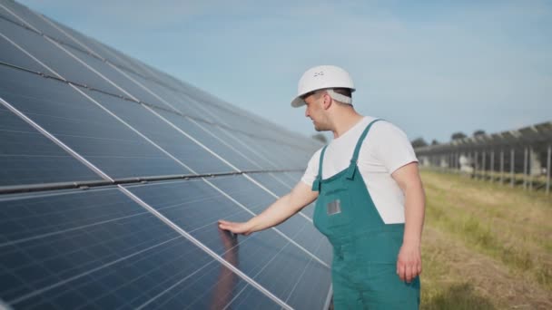 Assistentie technisch medewerker in uniform controleert een werking en efficiëntie prestaties van fotovoltaïsche zonnepanelen. Ingenieur reparatie en onderhoud fotovoltaïsche. Het project voor groene energie is gaande. — Stockvideo