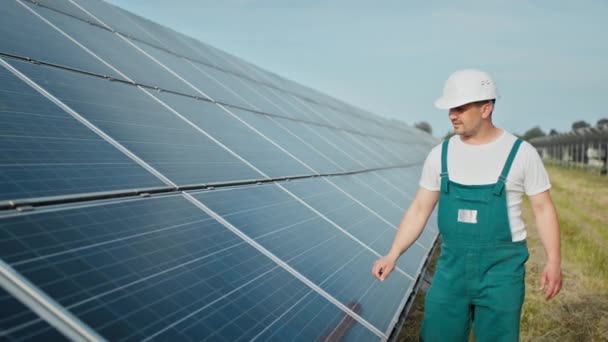 Ingeniero está comprobando el funcionamiento del sol y la limpieza de los paneles solares fotovoltaicos. Concepto energía renovable. Hombre caucásico en casco duro examinando paneles solares objeto. Concepto de energía verde — Vídeos de Stock