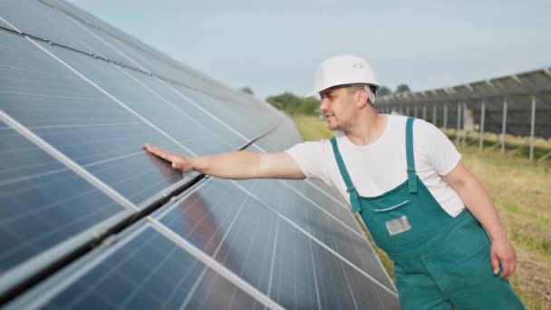 Retrato del orgulloso ingeniero industrial trabajador en uniforme de pie en el campo con grandes baterías solares. Granja ecológica. Central solar. Gente. Energía sostenible. Campo de energía solar. Ecología. — Vídeos de Stock