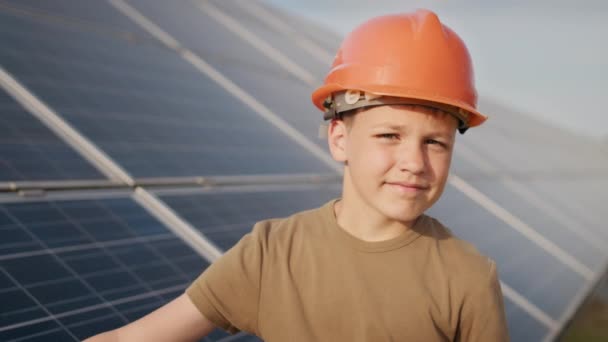 Chlapec v ochranné helmě ve sluneční elektrárně. Koncept dětí a zelené energie. Děti pro čistou energii. Střílení na solární elektrárnu. Ekologická farma. Solární elektrárna — Stock video