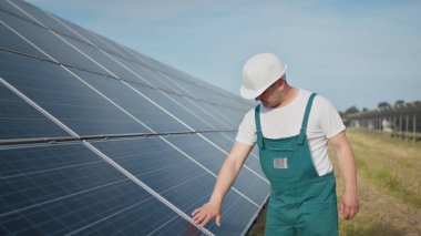 Üniformalı teknik görevli fotovoltaik güneş panellerinin faaliyet ve verimlilik performansını kontrol ediyor. Mühendis onarımı ve bakım fotovoltaiği. Yeşil enerji projesi devam ediyor.