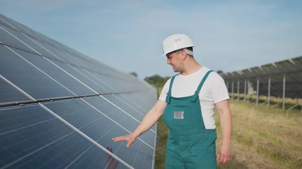 Virkapukuinen tekninen työntekijä tarkistaa aurinkosähköpaneelien toiminnan ja tehokkuuden. Insinööri korjaus ja huolto aurinkosähkö. Vihreän energian hanke on käynnissä. — kuvapankkivalokuva