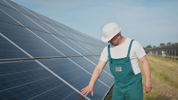 Bistandstekniker i uniform kontrollerer solcellepanelenes virkemåte og effektivitet. Reparasjon og vedlikehold av solcelleanlegg. Prosjektet Grønn energi pågår. – stockfoto