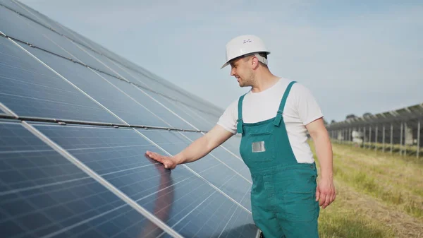 Insinööri asiantuntija aurinkoenergian aurinkosähköpaneelit. Mies kovassa kypärässä tutkii esinettä. Käsitys aurinkovoimalan kehittämisestä ja vihreästä energiasta. Teknologiaa. Ekologinen käsite. — kuvapankkivalokuva