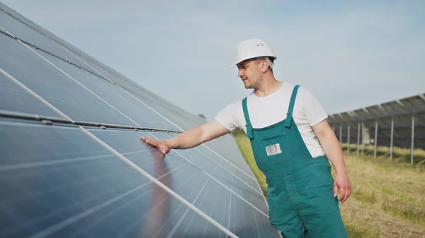 Insinööri asiantuntija aurinkoenergian aurinkosähköpaneelit. Mies kovassa kypärässä tutkii esinettä. Käsitys aurinkovoimalan kehittämisestä ja vihreästä energiasta. Teknologiaa. Ekologinen käsite. — kuvapankkivalokuva
