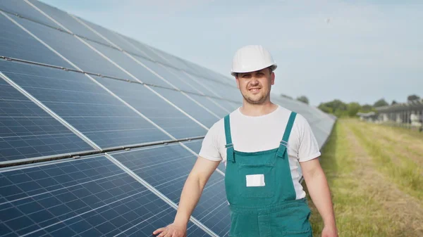 Retrato de orgulhoso engenheiro industrial trabalhador em uniforme de pé no campo com grandes baterias solares. Fazenda ecológica. Central de energia solar. Gente. Energia sustentável. Campo de energia solar. Ecologia. — Fotografia de Stock