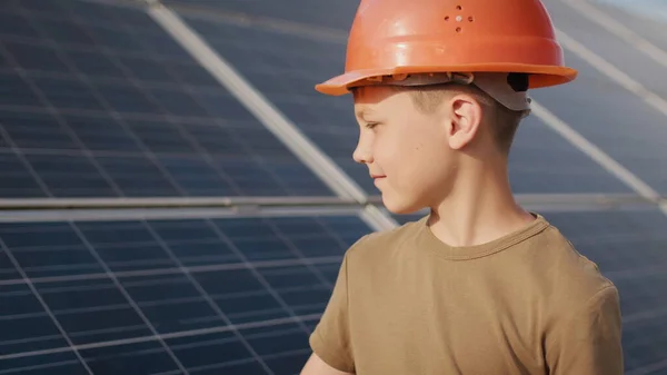 Pieni poika suojakypärässä aurinkovoimalassa. Käsite lasten ja vihreää energiaa. Lapset puhtaasta energiasta. Ampuminen aurinkovoimalassa. Ekologinen maatila. Aurinkovoimala — kuvapankkivalokuva