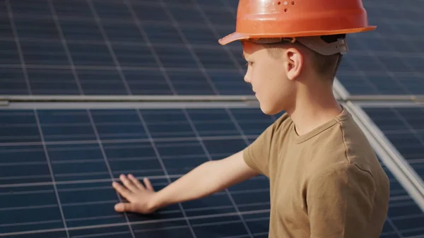 Pieni poika suojakypärässä aurinkovoimalassa. Käsite lasten ja vihreää energiaa. Lapset puhtaasta energiasta. Ampuminen aurinkovoimalassa. Ekologinen maatila. Aurinkovoimala — kuvapankkivalokuva