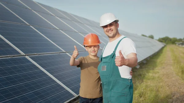 พ่อวิศวกรหนุ่มคนหนึ่งกําลังอธิบายให้ลูกชายของเขาฟังถึงการดําเนินงานและประสิทธิภาพของแผงโซลาร์เซลล์แสงอาทิตย์ในตอนพระอาทิตย์ตก แนวคิด: พลังงานหมุนเวียน เทคโนโลยี ไฟฟ้า สีเขียว อนาคต ครอบครัว . — ภาพถ่ายสต็อก