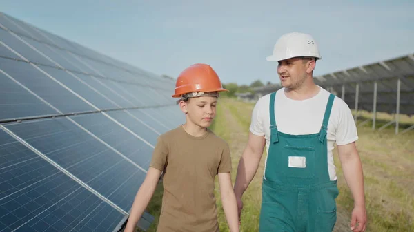 Insinööri-isä selittää pojalleen aurinkopaneelien toimintaa ja suorituskykyä. Ekologisen uusiutuvan energian käsite ja laadukas perheaika. Konsepti: uusiutuva energia — kuvapankkivalokuva