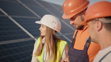 Ekolojik istasyon. Alternatif enerji. Mühendisler güneş çiftliğinde özel üniformalı çizimler yapıyorlar. Etrafa bakıyorlar ve güneşli bataryaların kurulumunu tartışıyorlar. Güneş panelleri alanı