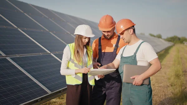 Ingeniører bruker tegninger på solfarmen med et spesielt, ensartet blikk rundt omkring for å diskutere installasjon av solfylte batterier - miljømessig treg bevegelse. Møte med investor – stockfoto