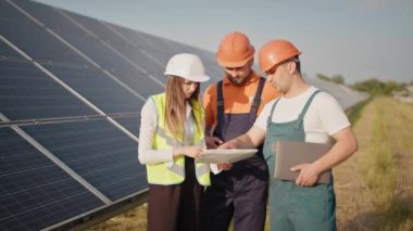 Mühendisler güneş çiftliğinde özel üniformalı çizimler yapıyorlar. Etrafa bakıyorlar. Güneşli bataryaların kurulumunu tartışıyorlar. Yatırımcıyla görüşme
