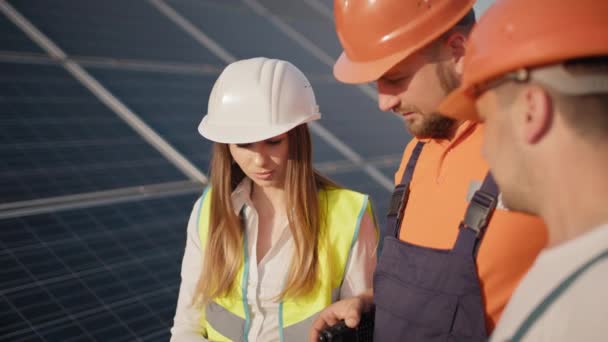 生态站替代能源。工程师们穿着制服站在太阳能发电厂的图纸上环顾四周，讨论太阳能电池的安装问题。太阳能电池板场 — 图库视频影像