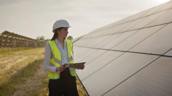 Kobieta inżynier ekologiczny wykorzystuje dokumenty projektowe i pliki oraz gromadzi efektywne informacje o panelach słonecznych. Fotowoltaiczna farma słoneczna. Zielona energia. Środowisko. Pojęcie zielonej energii — Zdjęcie stockowe