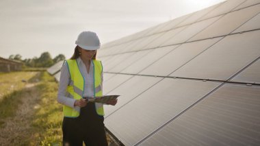 Kadın ekoloji mühendisi proje belgeleri ve dosyaları kullanır ve güneş panelleri hakkında verimli bilgiler toplar. Fotovoltaik güneş çiftliği. Yeşil enerji. Çevre. Yeşil enerji kavramı