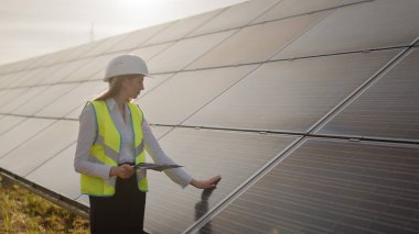 Kadın ekoloji mühendisi proje belgeleri ve dosyaları kullanır ve güneş panelleri hakkında verimli bilgiler toplar. Fotovoltaik güneş çiftliği. Yeşil enerji. Çevre. Yeşil enerji kavramı