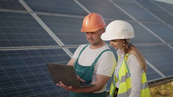 技术员和投资人在太阳能电池农场通过太阳能电池板现场检查太阳能电池板。发电厂的员工和太阳能电池板的设计. — 图库照片