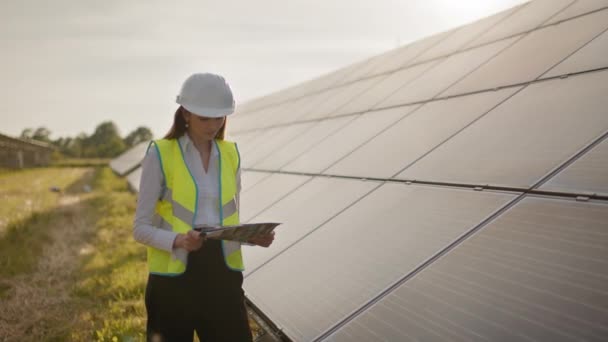 Женщина-инженер-эколог использует проектные документы и файлы и собирает эффективную информацию о солнечных батареях. Фотоэлектрическая солнечная ферма. Зеленая энергия. Окружение. Концепция зеленой энергии — стоковое видео