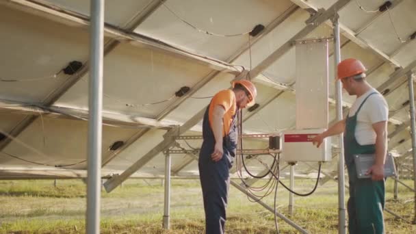 Trabajadores instalando PV Fotovoltaica, paneles solares, que convierte la energía solar en energía eléctrica. Conexión y configuración de paneles solares a la red. Concepto de energía verde. — Vídeo de stock