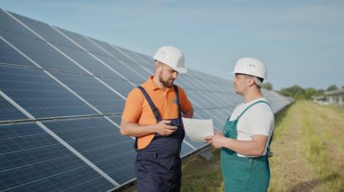 Güneş enerjisindeki güneş pili panellerini kontrol eden enerji teknisyeni. Güneş Çeviriciden Fabrika Elektrik 'e güneş enerjisi. Bir enerji santralinin çalışanı telsizle komutları iletir..