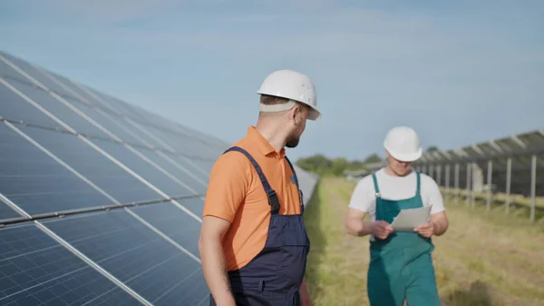 Coworking ingeniører på solkraftverk. Voksne menn i hatt, en ansatt i et kraftverk sender kommandoer via walkie-talkie. Transport av ren energi. Ren energi. Solfylte batterier. – stockfoto