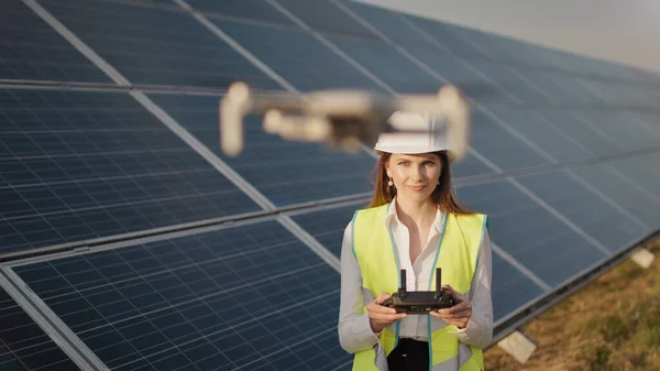 Ingeniørkvinne i hardhatt holder nettbrett datamaskin opererer flyvende drone i solkraftverk. Installasjon av solcellepaneler. Solceller. Ny teknologi. Investor kontrollerer solkraften – stockfoto