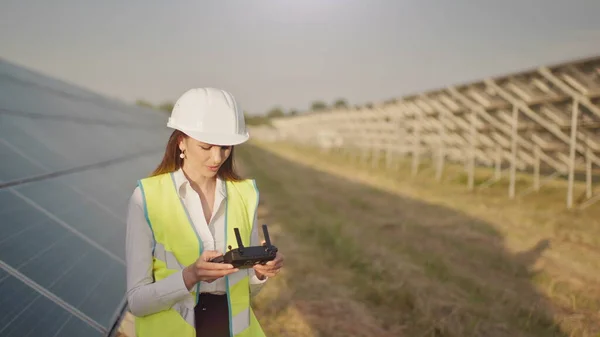 Ingeniørkvinne i hardhatt holder nettbrett datamaskin opererer flyvende drone i solkraftverk. Installasjon av solcellepaneler. Solceller. Ny teknologi. Investor kontrollerer solkraften – stockfoto