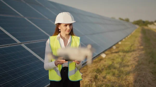 รูปภาพของวิศวกรหญิงที่ปฏิบัติการโดรนบนพื้นหลังของโรงไฟฟ้าพลังงานแสงอาทิตย์ การติดตั้งแผงโซลาร์เซลล์แสงอาทิตย์ อาร์เรย์แสงอาทิตย์ เทคโนโลยีใหม่ นักลงทุนและวิศวกรแรงงาน — ภาพถ่ายสต็อก