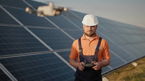Teollisuuden asiantuntija yllään kypärä ja ohjaus drone aurinkosähkövoimalassa. Aurinkopaneelien asennus. Teknologiat ja ekologia. Uudet teknologiat — kuvapankkivalokuva