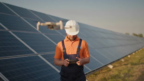 Industriekspert med hjelm og dronekontroll i solcelleanlegg. Solpaneloppstilling. Teknologi og økologi. Kvinnelig investor sjekker arbeidet – stockfoto