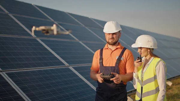 Expert industrial care poartă cască și controlează drona în centrala solară fotovoltaică. Instalare panouri solare. Tehnologii și ecologie. Investitorul feminin verifică activitatea — Fotografie, imagine de stoc
