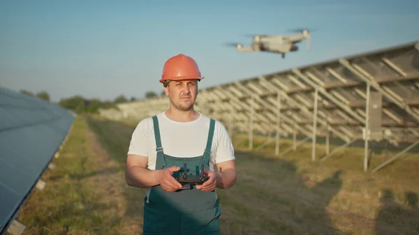 Inginer în hardhat care deține calculator tabletă care operează dronă zburătoare în instalația solară. Instalare panou solar fotovoltaic. Array solar. Noi tehnologii. Portretul unui inginer de drone — Fotografie, imagine de stoc