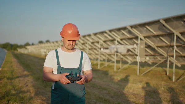 Pracownik elektrowni słonecznej rozmawia przez krótkofalówkę, podczas gdy jego koledzy i inwestor sprawdzają elektrownię słoneczną skanerem podczerwieni, dronem. Portret pracownika inżynierii dronów — Zdjęcie stockowe
