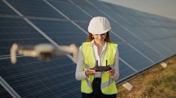 Egy női mérnök portréja, aki egy drónt működtet egy naperőmű hátterében. Fotovoltaikus napelem telepítés. Szoláris tömb. Új technológiák. Befektető és mérnök Stock Kép