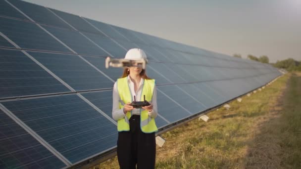 Ingenjör kvinna i hårdhatt innehav tablett dator som driver flygande drönare i solkraftverk. Solcellspanelinstallation. Solpaneler. Ny teknik. — Stockvideo