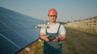 Bir güneş enerjisi santralinin çalışanı bir telsizle konuşurken meslektaşları ve bir yatırımcı güneş enerjisi santralini kızılötesi tarayıcı, bir İHA ile kontrol ediyorlar. İHA mühendisi portresi