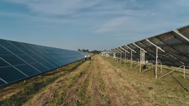 Vista superior de especialistas caminhando através de uma usina de energia solar. Três funcionários de usina de energia alternativa andando e falando sobre o esquema de painéis solares. Trabalho de equipa. Grupo de especialistas. — Vídeo de Stock