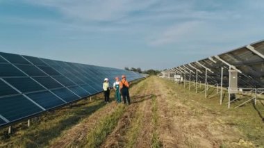 Endüstriyel mühendislerden oluşan bir iş ekibi güneş çiftliğinde yürüyor ve verimli bir inşaat planı üzerinde tartışıyorlar. Alternatif enerji santralinin üç çalışanı yürüyor ve güneş panelleri şeması hakkında konuşuyor.
