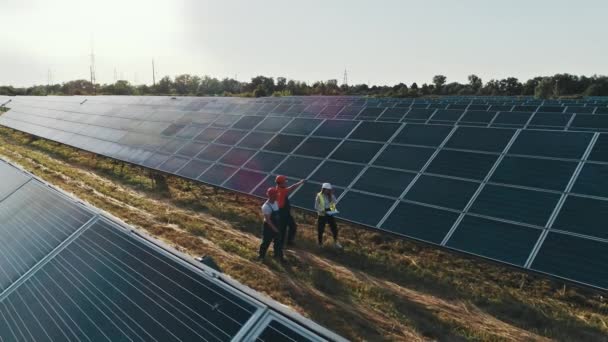 Vista superior de especialistas caminando a través de una planta de energía solar. Equipo empresarial de ingenieros industriales caminando en la granja solar y discutiendo plan eficiente de construcción. Concepto de energía solar. — Vídeos de Stock