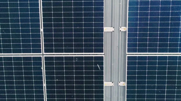 Mavi fotovoltaik güneş panellerinin yüzeyi, temiz ekolojik elektrik üretmek için çatıya monte edildi. Yenilenebilir enerji konsepti üretimi. Güneş panellerinin İHA Hava Görüntüsü — Stok fotoğraf
