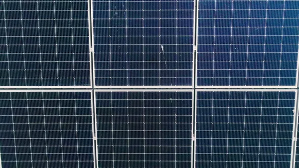 A tiszta ökológiai elektromosság előállítása céljából az épülettetőre szerelt kék fotovoltaikus napelemek felületének közelsége. A megújuló energia koncepciójának kidolgozása. Napelemek drónantenna-nézete — Stock Fotó
