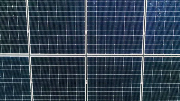 Primer plano de la superficie de los paneles solares fotovoltaicos azules montados en el techo del edificio para producir electricidad ecológica limpia. Concepto de producción de energías renovables. — Foto de Stock