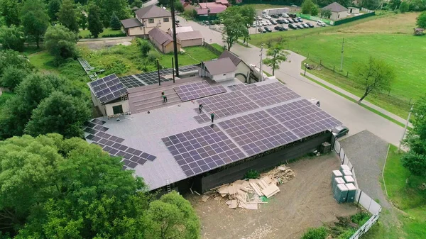 Werknemers installeren zonnepanelen op het dak van een huis, dat zonne-energie omzet in elektrische energie. Concept van werk. Werknemers in speciale outfit lopen en praten over zonnige cellen installatie — Stockfoto