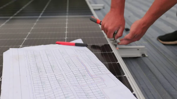 Nahaufnahme des Arbeiters bei der Installation und Wartung der installierten Photovoltaikanlage. Im Vordergrund steht ein Diagramm der Installation von Sonnenkollektoren. Sonnenkollektoren auf dem Dach. — Stockfoto