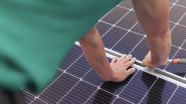 Aurinkopaneelien asennus, liittäminen ja asennus. Työntekijät kiinnittävät aurinkopaneelit. Teknikot asentamassa aurinkopaneeleita metalliseen telineeseen. Aurinkopaneeleja talon katolle asentavat työntekijät — kuvapankkivalokuva